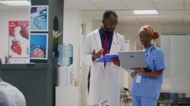 Medical staff team looking at insurance files in hospital lobby, using registration papers and reports to treat patients with disease. Medical workers meeting in waiting area at clinic.