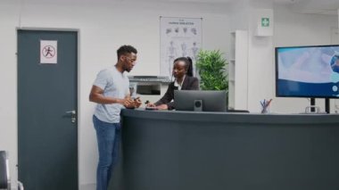 Male patient using mobile phone to pay with nfc on pos terminal, making transaction for medicine or treatment. Person using contactless payment after having checkup visit at health center.