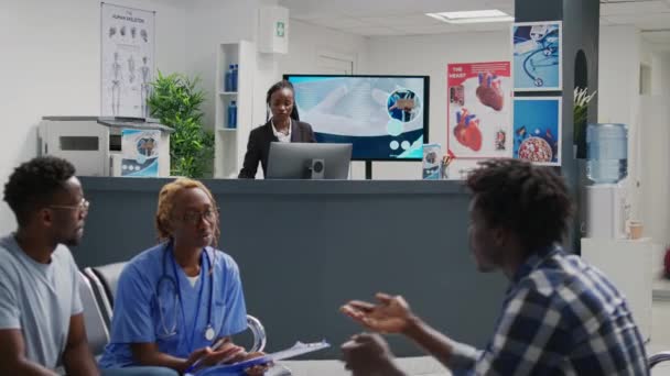 在医院接待处工作的非裔美国人接待员 接听固定电话 为病人预约 使用前台登记表的女性设施员工 — 图库视频影像