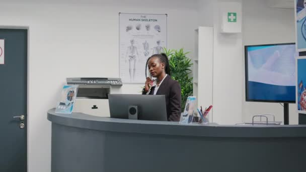 Young Health Center Employee Working Reception Desk Answering Landline Phone — 비디오