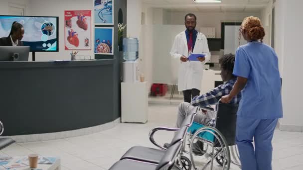 Медсестра Допомагає Афроамериканському Пацієнту Інвалідністю Готує Користувача Інвалідного Візка Огляду — стокове відео