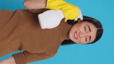 Vertical video: Cleaning woman pointing and showing cleaning product or isolated text, using spray bottle filled with sanitary solution to disinfect surfaces and prevent the spread of germs