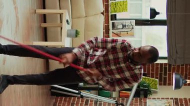 Vertical video: Diverse people vacuuming floors and cleaning furniture on shelves, sweeping mess or dirt with tools. Man and woman using vacuum cleaner with suction, gloves and rags to clean household