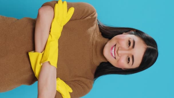 垂直视频 穿着橡胶防护手套的职业女性微笑着站在工作室的蓝色背景与手臂交叉 快乐的亚洲人对顾客非常关心 — 图库视频影像