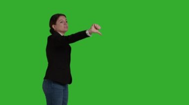 Side view of corporate employee giving thumbs down symbol in studio, doing dislike and negative bad gesture. Businesswoman with office suit expressing disapproval and disagreement on camera.