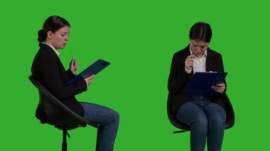 Confident businesswoman sitting on chair and analyzing papers, thinking about notes on clipboard files. Young manager acting thoughtful looking at official corporate documents, green screen.