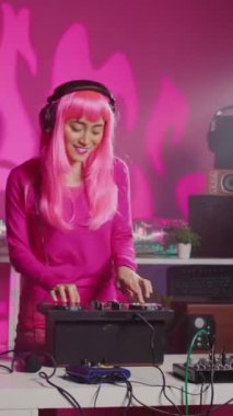 Vertical video: Smiling dj artist wearing headphones during performance, mixing eletronic sound with techno playing music at professional mixer console. Musician enjoying partying at night in club