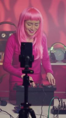 Vertical video: Performer recording music session with smartphone camera, mixing and mastering electronic sound preparing eletronic concert. Musician performing techno song using professional audio