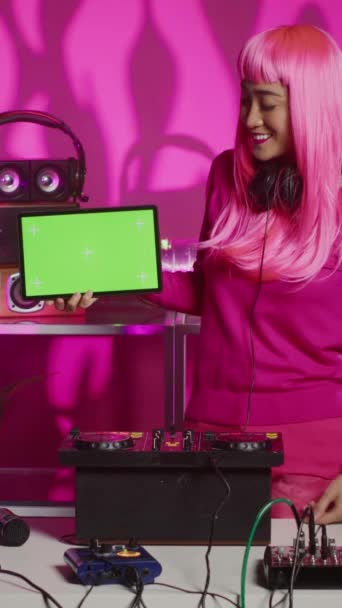垂直ビデオ 緑色の画面のクロマキーを押した笑顔Djは ナイトクラブで新しいアルバムを促進する電子とテクノサウンドを混合しながら 孤立ディスプレイとタブレットをモックアップします プロを用いた音楽家 — ストック動画