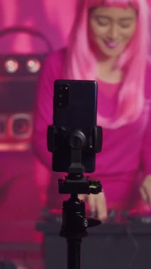 Vertical video: Musician recording music session with phone camera, mixing and mastering electronic sound preparing eletronic album. Artist performing techno song using professional audio equipment
