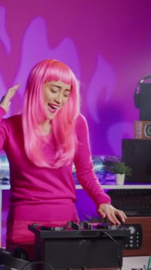 Vertical video: Artist creating musical performance with remix music using professional mixer console, having fun at night in club. Asian musician standing at dj table performing electronic song