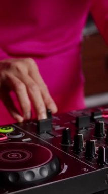 Vertical video: Performer creating unique techno sound using mixer console, performing at eletronic party in club at night. Asian musician playing remix song using professional audio equipment. Music