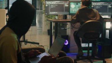 Cyber criminals using trojan virus to hack computer system, trying to steal data and passwords. Team of spies committing hacktivism and identity theft, making threats at night.