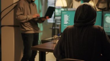Thieves with anonymous masks hacking computer to steal information directly from government system, cybercrime. Masked cyber criminals using malware to break into online software.