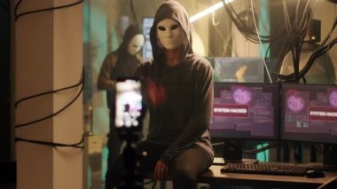 Female thief with mask broadcasting live threat video, asking for ransomware instead of leaking important information. Young masked person threatening to expose passwords, cybercrime. Handheld shot.