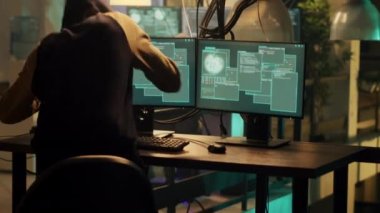 Happy skilled man planning security breach to take important information without authorization. Male hacker doing espionage and breaking into computer system with dark web. Handheld shot.