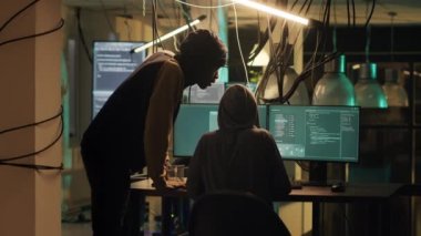 Cyber criminals working at night to break security encryption on computer, trying to steal government information for hacktivism. Team of spies hacking network system server. Tripod shot.