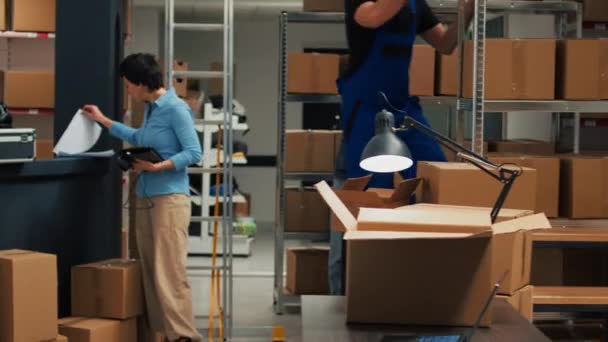 男性倉庫労働者は 商品在庫や商品物流を計画するためにラップトップを使用して パッケージに物資を配置します 段ボール箱に製品を入れる起業家 株式管理 — ストック動画