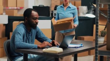 Diverse employees shipping storage products from warehouse, looking at merchandise in boxes before sending package order. Checking inventory and stock, working on distribution logistics.