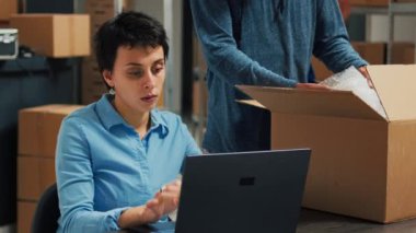 Diverse team of partners putting products in boxes and checking quality before shipping order to clients. Man and woman planning shipment with merchandise in packages, delivery logistics.