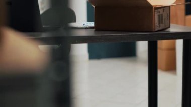 Empty warehouse office space filled with cardboard boxes and products, storage shelves with merchandise and goods. Storehouse used for supply management and shipping logistics. Handheld shot.