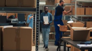 Business owner arranging merchandise in cardboard packages, putting products in boxes for shipment. Male entrepreneur using goods and supplies from warehouse racks, raw materials.