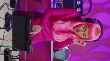 Vertical video: Musician using cutting-edge technology to remix music, creating unique sound for fans during electronic party in night club. Asian performer mixing techno remix, dancing and having fun