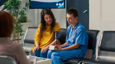 Nabız basıncı ve hipertansiyonu ölçmek için tonometre kullanan bir tıp asistanı kardiyoloji ve kardiyak test yapıyor. Uzman ve Asyalı hasta check-up ziyaretine katılıyor..