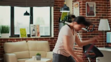 Modern housewife acting funny mopping living room floors, sweeping dirt and dust with mop and having fun. Young adult smiling, listening to music and dancing at home, cleaning apartment.