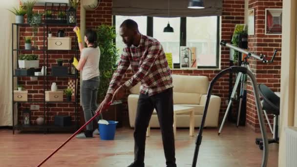 Interracial Couple Vacuuming Floors Cleaning Furniture Shelves Sweeping Dust Dirt — Vídeo de Stock