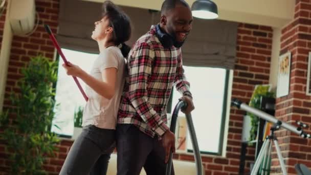 Mixed Race Couple Vacuuming Wooden Floors Showing Dance Moves Home — Stockvideo