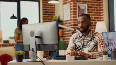 Genç bir çalışan evde uzaktan kumandayla rapor hazırlıyor, bilgisayarı kullanıyor ve yöneticiye e-posta gönderiyor. Şirket satışlarını analiz etmek ve bir kadınla uzaktan çalışmak. El kamerasıyla..
