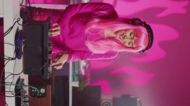 Vertical video: Smiling dj artist wearing headphones during performance, mixing eletronic sound with techno playing music at professional mixer console. Musician enjoying partying at night in club