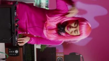 Vertical video: Artist recording mixing process with phone camera, performing eletronic music in night club using professional mixer console. Dj woman with pink hair having fun while performing techno
