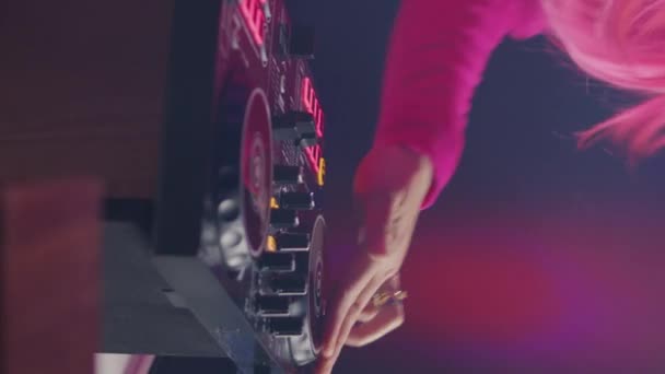 垂直ビデオ Djテーブルに立っているミュージシャンは ピンクの背景にスタジオでプロのターンテーブルで電子曲を演奏します アジアのアーティストがテクノミュージックを演奏し クラブで夜を楽しむ — ストック動画