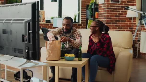 African American Couple Eating Burgers Fries Home Having Fun Watching — Stock video