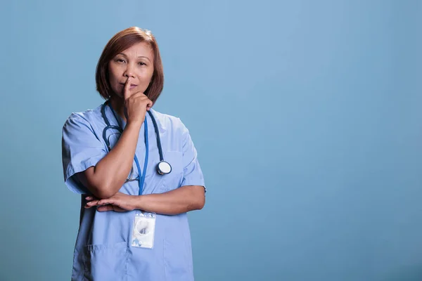 Pensive medical assistant wearing blue uniform thinking about health care treatment to cure sick patient during appointment. Thoughtful nurse brainstorming ideas, doubt expression. Medicine concept
