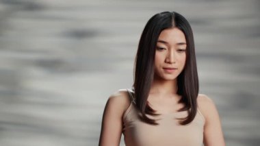 Asian beauty model posing for skincare ad in studio, woman with radiant and luminous skin feeling confident. Beautiful positive girl creating empowering, uplifting bodycare campaign.
