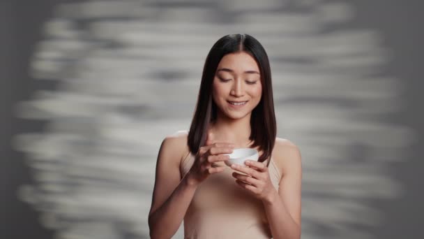 Glowing Asian Lady Applying Moisturizing Face Cream Promote Skincare Routine — Vídeo de stock