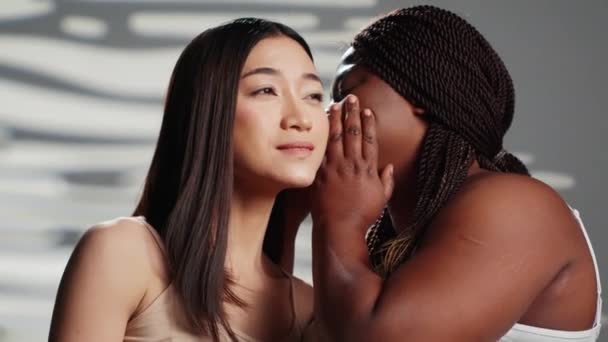 African American Woman Sharing Secret Asian Girl Creating Skincare Self — Wideo stockowe