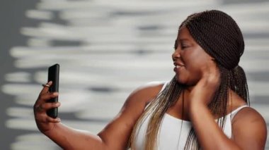 Young beauty model posing on mobile phone camera, acting funny and showing body confidence. Happy beautiful woman being flawless and positive, expressing self body acceptance.