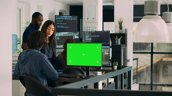 Team of programmers working on source code with greenscreen monitor in cloud computing office. App developers checking isolated chromakey display with copyspace and html script. Tripod shot.