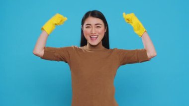 Overjoyed housekeeper wearing protective gloves while doing win gesture in front of camera after finishing housecleaning. Happy maid is a woman who is responsible for providing cleaning services