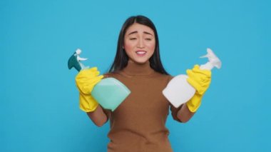 Cheerful house cleaner wearing yellow rubber gloves while showing chemical detergent spray in front of camera, promoting cleaning product. Professional housekepper worked hard to maintain a clean home