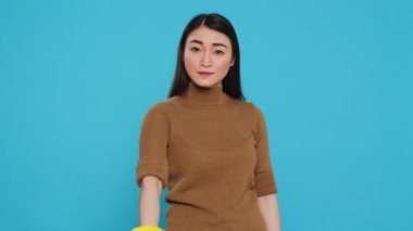 Joyful maid posing in studio doing approve gesture in front of camera after finishing cleaning customer house. Housekeeper is careful to use only the safest and effective cleaning products