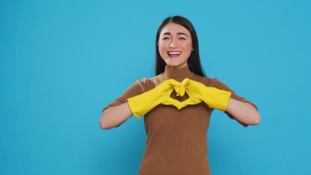 Happy Asian Maid Wearing Yellow Gloves While Doing Heart Shape — Stockvideo