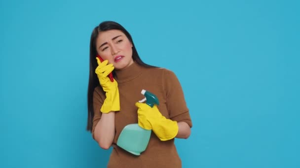 Азиатская Домохозяйка Разговаривает Телефону Носит Защитные Перчатки Держа Бутылку Моющим — стоковое видео