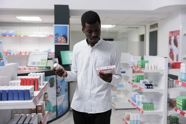 Young African American Man Choosing Heart Medication Drugstore Reading Instruction — Stockfoto
