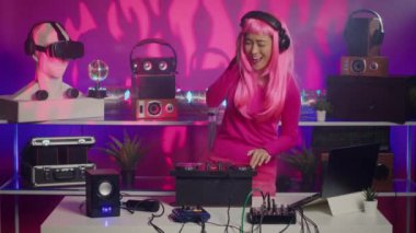 Performer using cutting-edge technology to remix music, creating unique sound for fans during techno party in night club. Asian musician mixing electronic remix, dancing and having fun