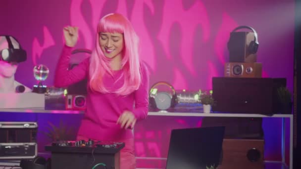 ミキサーでDjプレイし オーディオ機器を使用してテクノとエレトロニックサウンドを混合する陽気ミュージシャンとして働く ピンク色の髪をしたアジアのアーティストは 夜にクラブで演奏を楽しんでいます — ストック動画